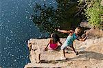 Young couple throwing stones from rock ledge, Hamburg, Pennsylvania, USA