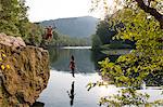 Young couple jumping from rock ledge, Hamburg, Pennsylvania, USA