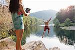 Woman photographing boyfriend jumping from rock ledge, Hamburg, Pennsylvania, USA