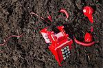 Red retro telephone buried in soil