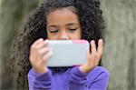 Close up of young girl in park playing hand held video game