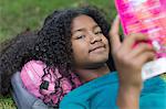 Close up portrait of young girl reading in park