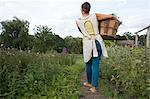 Woman carrying basket of plants on family herb farm