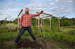 Mature man holding rake on herb farm