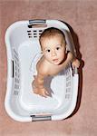 Baby girl standing in laundry basket, high angle