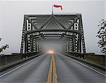 Car emerging from misty bridge