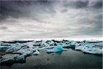 View of the lagoon Jokulsarlon glacial lake, landscape with reflections on the sea, blue iceberg and sky with gray clouds, Jokulsarlon, Skaftafell, Iceland, Europe