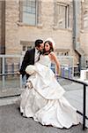 Groom kissing bride outdoors next to buildings, Toronto, Ontario, Canada