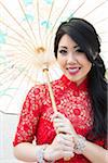 Close-up portrait of young woman holding Chinese parasol, smiling and looking at camera, Ontario, Canada