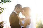 Close-up portrait of bride and groom standing outdoors, face to face, smiling and embracing, Ontario, Canada