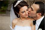 Close-up portrait of groom kissing bride on cheek, outdoors in Autumn, Ontario, Canada