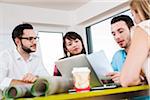 Close-up of group of young business people sitting around table, meeting and in discussion, Germany