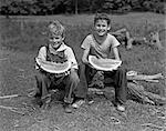 1940s TWO SMILING BOYS EATING WATERMELONS LOOKING AT CAMERA