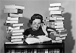 1950s WOMAN SITTING BETWEEN STACKS OF BOOKS PULLING DOWN GLASSES TO LOOK OVER RIMS