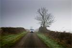 BMW 5-series car drives along empty country road in adverse foggy weather, Oxfordshire,  England, United Kingdom