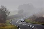 Car drives along foggy road, Oxfordshire,  United Kingdom