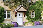 Typical cottage doorway and porch with aubretia shrubs in Stanton village, The Cotswolds, Gloucestershire, England, United Kingdom