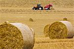 Tractor pulls a round baler to create straw bales, Cotswolds, United Kingdom