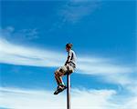 Man sitting and balancing on top of a metal post, looking towards expansive sky, on Surprise Mountain, Alpine Lakes Wilderness, Mt. Baker-Snoqualmie national forest.