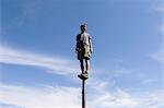 Man standing and balancing on a metal post, looking towards expansive sky, Surprise Mountain, Alpine Lakes Wilderness, Mt. Baker-Snoqualmie National forest.