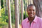 Trees on the shores of a lake. A man smiling at the camera.