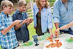 Organic Farm. An outdoor family party and picnic. Adults and children. Plate of pizza.