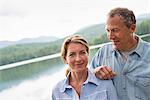 A mature couple standing by a lake shore.