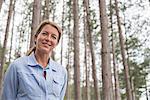 A woman standing among the trees on the shore of a lake in New York state.