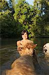 A woman swimming with her two dogs in a lake.