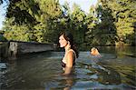 A woman swimming with her two dogs in a lake.