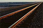 Railroad tracks extending across the flat Utah desert landscape, at dusk.