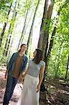 Two people, a young woman and man, walking side by side in the woods.