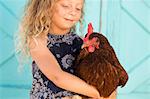 A young girl holding a chicken in her arms.