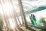 A couple walking in woodland on the shores of a lake.