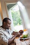 A man sitting in a cafe with a cup of coffee. Using a smart phone.