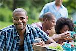 A group of adults and young people at a meal in the garden of a farmhouse.