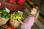 Working on an organic farm. A young blonde haired woman sorting different types of bell pepper for sale.