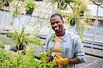 Working on an organic farm. A man tending young plants in a glass house.