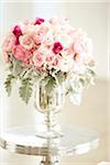 Bouquet of pink roses in silver vase on silver table, studio shot