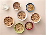 Overhead view of bowls of a variety of healthy cereals and jug of milk, studio shot