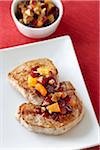 Porkchops on Plate dressed with Cranberries, Walnuts, and Dried Apricots, Bowl of extra Dressing in the background