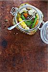 Overhead Shot of Antique Jar of Pickled Vegetable Relish with Green Beans, Carrots, Cauliflower, Thyme, Bay Leaf, Peppercorns and White Onions in Vinegar