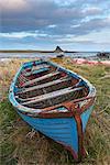 Old fishing boat pulled up on the shore at Holy Island, with the castle across the bay, Lindisfarne, Northumberland, England, United Kingdom, Europe