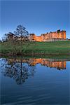 Alnwick Castle reflected in the River Aln at twilight, Northumberland, England, United Kingdom, Europe