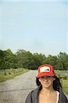 Young Woman in Cap Standing on Country Road