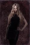 sexy young woman with mystery look and dark dress posing with long blonde hair and creative make-up. Halloween style