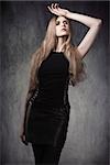 attractive blonde woman in fashion pose with Halloween style, long blonde hair, dark make-up and sexy gothic clothes