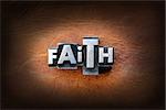 The word faith made from vintage lead letterpress type on a leather background.
