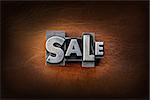 The word sale made from vintage lead letterpress type on a leather background.