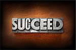 The word succeed made from vintage lead letterpress type on a leather background.